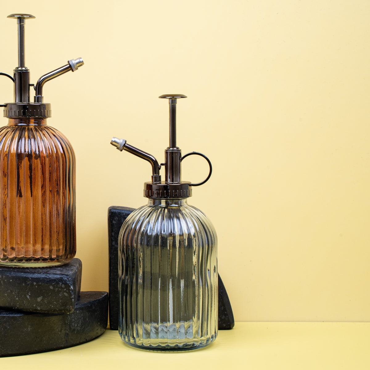 Sprühflasche Pflanzen - Stilvolle Sprühflaschen aus Glas und Metall auf einem Tisch